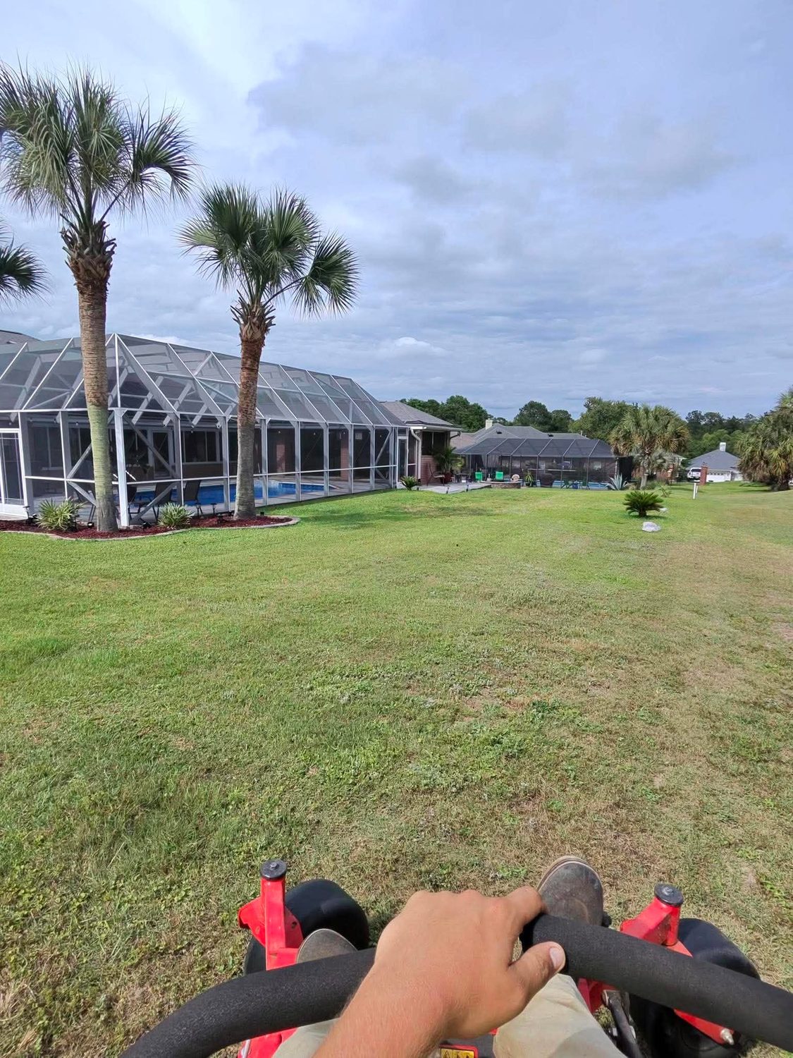 Mowing a large lawn near a pool enclosure